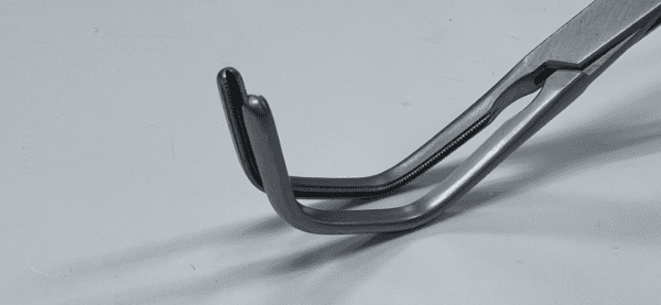 A pair of LAMBERT-KAY AORTIC CLAMP tweezers on a white surface.