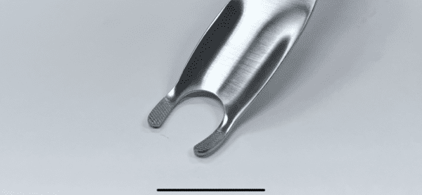 A femoral elevator, proximal, narrow, standard prongs on a white surface.
