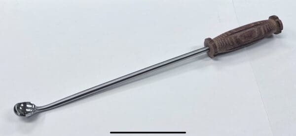 A LARGE BONE CURETTE with a wooden handle on a white surface.