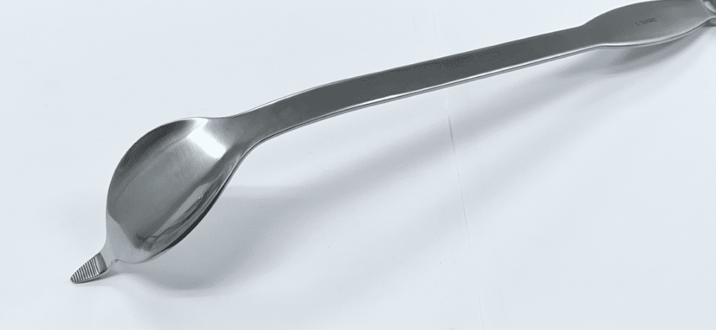 A COBRA RETRACTOR spoon on a white surface.