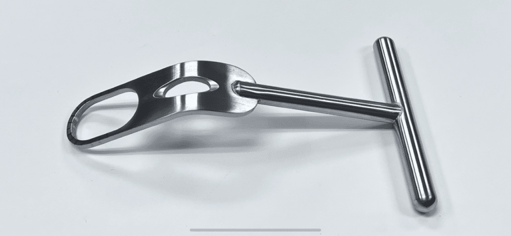 A stainless steel FUKUDA RETRACTOR, MODIFIED on a white surface.