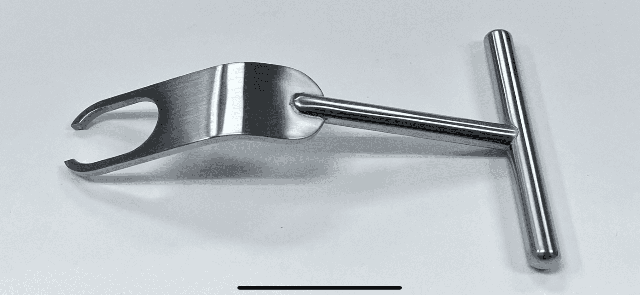 A FUKUDA RETRACTOR, HALF RING handle on a white surface.