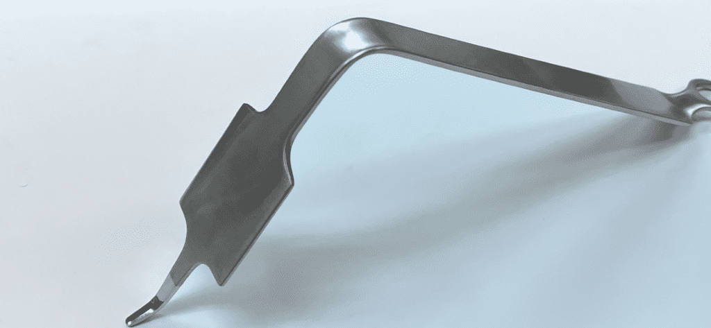 An image of a Hohmann retractor, bent, wide on a white surface.
