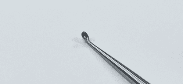 A SPINAL FUSION CURETTE, ANGLED is sitting on top of a white surface.