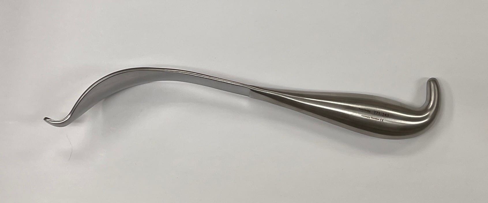 An AUFRANC COBRA RETRACTOR with a curved shape hanging on a wall.