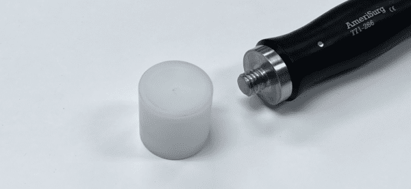 A black and white FEMORAL HEAD IMPACTOR next to a white object.