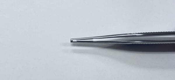 A CALLISON ADSON TISSUE AND TYING FORCEP with a metal tip sitting on top of a white surface.