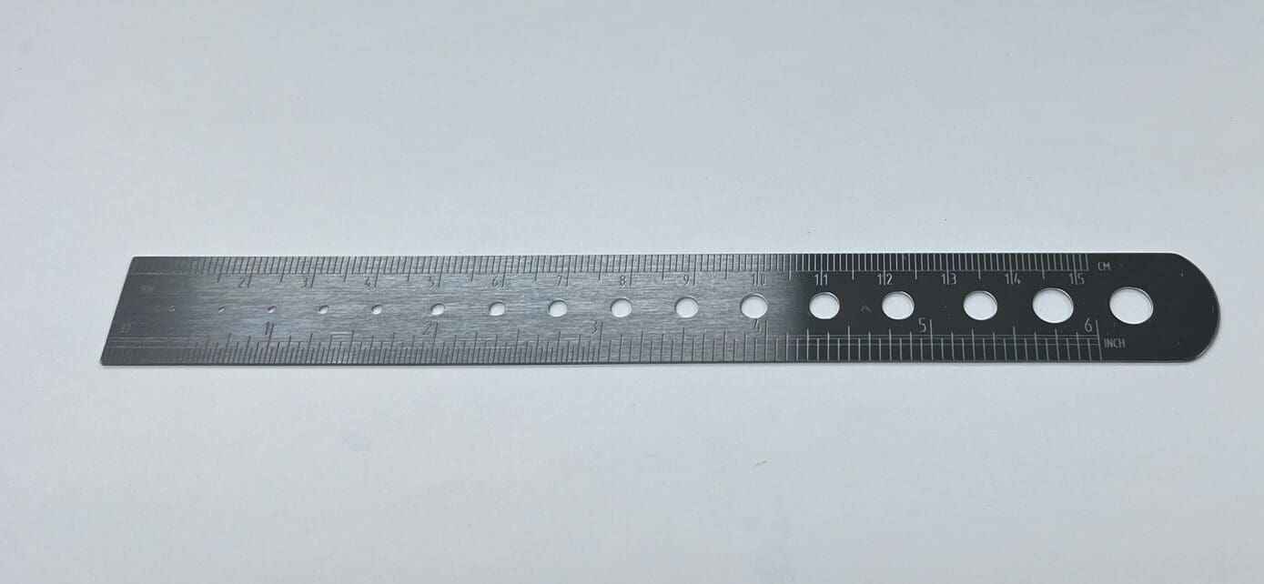 A RULER, K-WIRE AND PIN GAUGE with holes on it on a white surface.