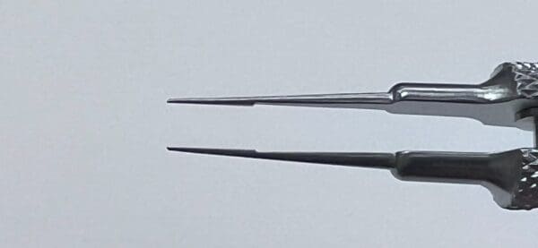 A pair of TENNANT TYING FORCEPs on a white surface.