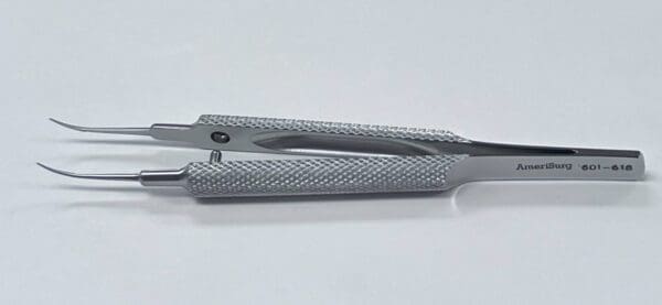 A pair of TENNANT TYING FORCEP tweezers on a white surface.