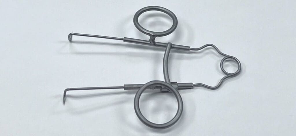 A pair of SPRING RETRACTOR hooks on a white surface.